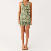 Green leaf-patterned dress worn by a model on a white background